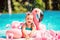 Smiling toddler girl swimming in the pool with pink flamingos