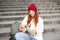 Smiling tourist, girl sits on stairs, rests on staircase, takes thermos from backpack, drinks hot coffee from flask