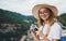 Smiling tourist girl walking in nature outdoor hold in hands retro camera, young blonde woman in hat and glasses leisure vacation