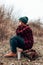 Smiling trail hiker woman camping in the forest and relaxing near campfire in nature, drinking hot tea. Outdoor activity