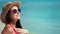 Smiling travel fashion woman in hat sunglasses sunbathing enjoying sea view having positive emotion
