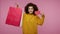 Smiling trendy girl afro hairstyle in hoodie raising shopping bags and Sale word, looking satisfied with purchase