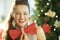 Smiling trendy housewife holding red dinner napkin as bow tie