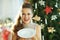 Smiling trendy housewife holding serving white dinner plate