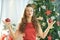 Smiling trendy woman near Christmas tree doing yoga