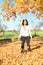 Smiling tropical girl standing under falling yellow leaves