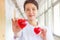 Smiling Two Red Hearts held by smiling female nurse`s hands, representing giving effort high quality service mind to patient.