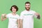 Smiling two young friends couple in white volunteer t-shirt isolated on pastel green background. Voluntary free work