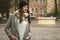 Smiling urban woman dressed in grey coat at the city