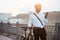 Smiling while using social medias. Businessman in formal clothes with black bicycle is in the city