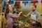 Smiling vendor giving tomatoes to woman at the counter in the grocery store