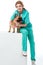 smiling veterinarian hugging french bulldog while sitting on white cube