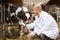 Smiling veterinary technician with dairy cattle in farm