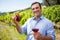 Smiling vintner holding grapes and glass of wine