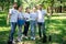 smiling volunteers with new trees watering can and shovel standing in park