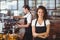 Smiling waitress with arms crossed in front of colleague