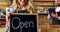 Smiling waitresses holding open sign board