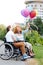 Smiling wheelchaired couple letting the balloons off