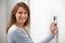 Smiling Woman Adjusting Thermostat On Home Heating System