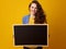 Smiling woman against yellow background showing blank board