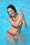 Smiling woman bathes in pool under water splashes