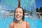 Smiling woman bathes in pool under water splashes