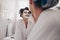 Smiling woman in bathrobe getting her facial done at home. Two women standing in bathroom with curly rollers pinned on hair