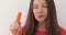 Smiling woman bites carrot studio portrait