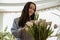 Smiling woman in blue shirt takes care of white tulips, home comfort