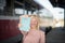 Smiling woman on the the bus station holding a books