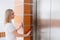 Smiling woman calling elevator of the residential building.