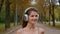 Smiling woman carefree girl positive happy Caucasian female runner listen song in earphones running in park run smile