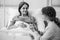 Smiling woman and caring daughter holding her hand in the hospital, black and white photo