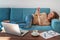 Smiling woman chatting lying on a blue sofa on smartphone. Young woman working from home