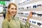 Smiling woman choosing sunglasses from shelf in eyewear store