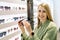 Smiling woman choosing sunglasses from shelf in eyewear store