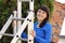 Smiling woman climbing on aluminum ladder in garden
