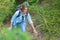 Smiling woman climbing on a mountain path. Plants and trees in the background. Active sports and tourism. Close up