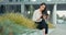 A smiling woman, company employee, secretary, sits on break in front of a corporate building, a wall of plants, a