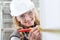 Smiling woman construction worker work with meter tape and pencil, measure wall in interior building site, wearing helmet, glasses