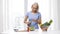 Smiling woman cooking vegetable salad at home