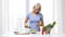 Smiling woman cooking vegetable salad at home