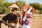 Smiling woman cowgirl with horse sitting on ranch