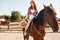 Smiling woman cowgirl riding horse in village