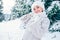 Smiling woman in cozy knitting pullover and fur hat stay om winter forest glade