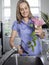 Smiling Woman Cutting Flowers In Kitchen Sink