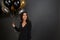 Smiling woman with dark hair is holding colorful balloons in hand, looks at copy space, knows how to celebrate new year better,