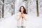 Smiling woman with dark hair in winter clothes with paper cup of coffee in hands against background of snowy winter forest