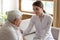 Smiling woman doctor supporting older patient, touching shoulder