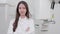 A smiling woman doctor in a white coat looks at the camera in a close-up image. At the x-ray room, a confident, skilled, and